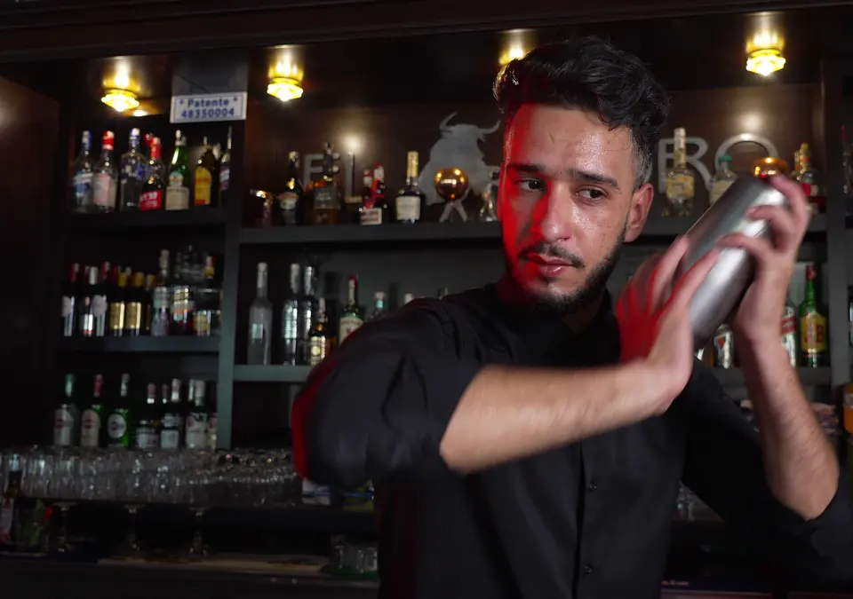 Le barman secoue un cocktail derrière le bar