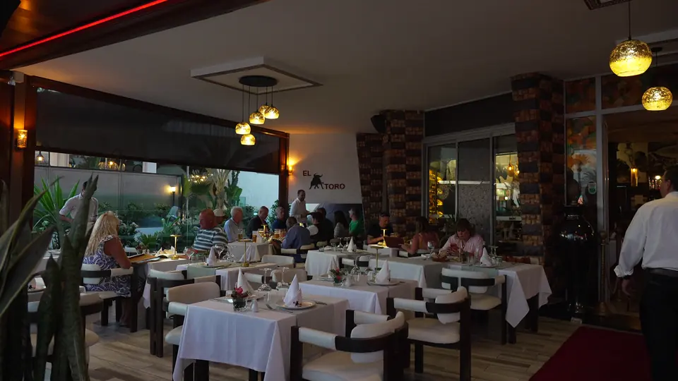 Des convives attablés devant les baies ouvertes sur les palmiers