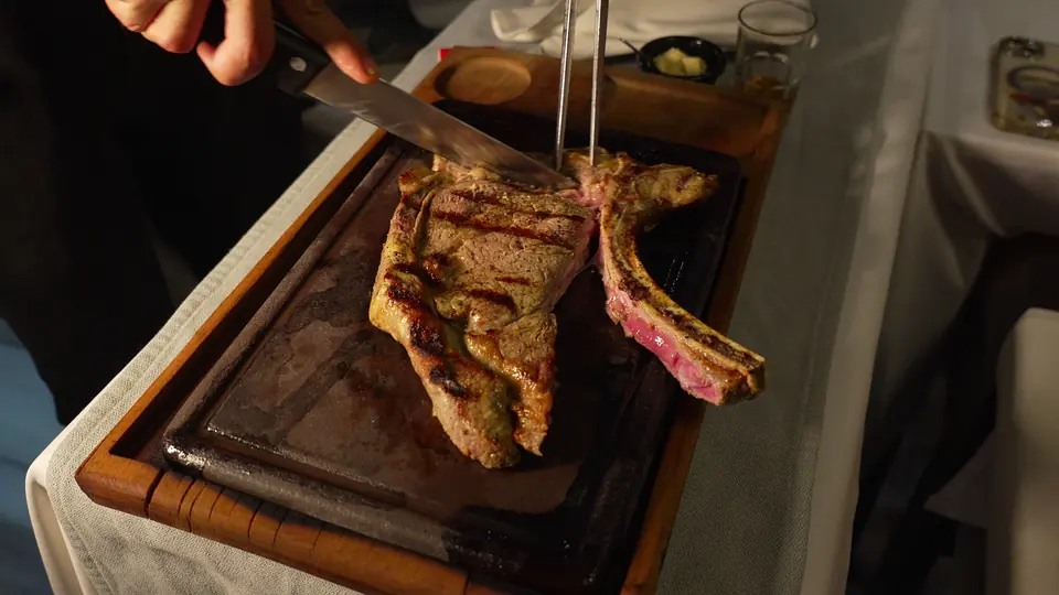 Un steak avec os découpé à table sur une planche en bois
