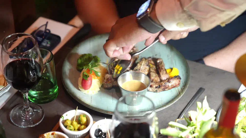 Viande grillée servie à table, avec un verre de vin rouge