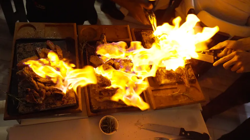 Plusieurs pièces de viande flambées sur leurs planches, flammes hautes