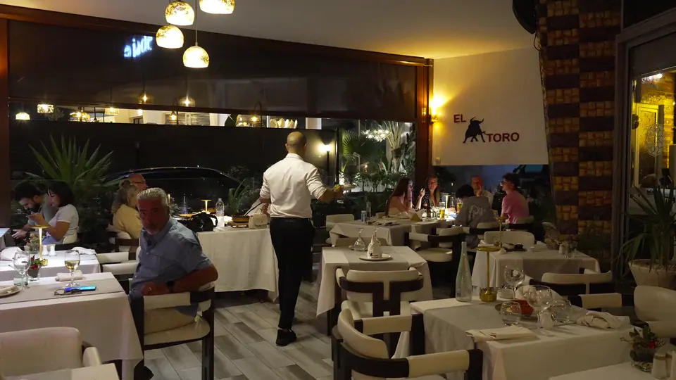 Un serveur entre les tables de la terrasse, de nuit