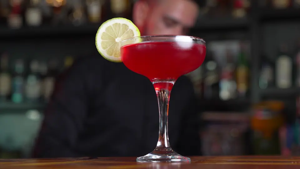 Cocktail rouge dans une coupe, garni d’une rondelle de citron